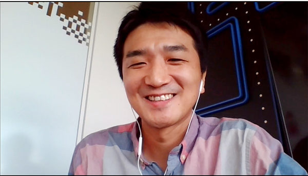Kubota sits in front of a wall decorated with a PAC-MAN maze during the video call interview.